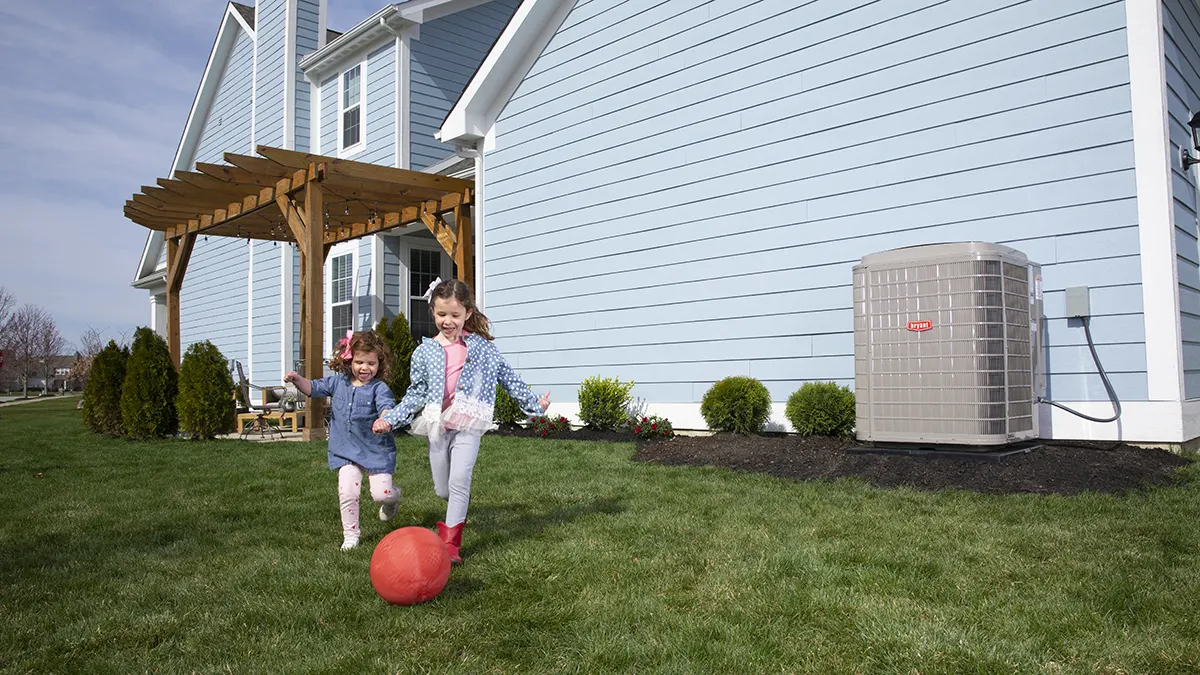 Kids playing with red ball by Bryant Air Conditioner Outdoor unit | Emerald Coast Air Conditioning and Heating | airconditioningrepairpensacola.com